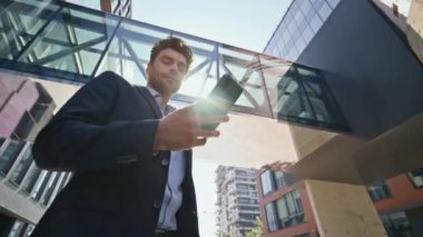 Modern kasaba bölgesindeki cep telefonu mesajlarını kontrol eden zarif bir yönetmen. Sokakta cep telefonu e-postalarını okurken gülümseyen rahat iş adamı. Mutlu adam maaş bordrosu alıyor. Kamera hareket ediyor.