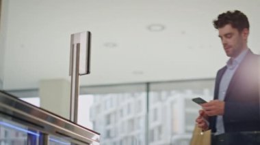 Yönetici, ofisin güvenlik kartını akıllı telefon ekranına geçirerek geçiyor. Elektronik kapılardan cep telefonuyla giren kendinden emin bir işadamı. Meşgul erkek yönetici işe giderken otomatik turnikeyi açar