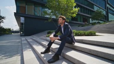 Rahatlamış ofis çalışanı kahve içiyor iş yerindeki sokak merdivenlerinde oturuyor ve zum yapıyor. Çok çalışan iş adamları, şirket binası yakınlarında rahatça içeceklerin alınmasından hoşlanırlar. Düşünceli adam kariyer gelişimi düşünüyor.