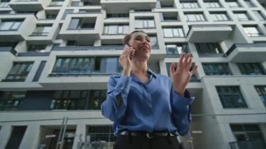 Modern şehir bölgesinde cep telefonundan konuşan öfkeli bir iş kadını. Huzursuz genç bayan, yerleşim alanından memnun olmayan cep telefonu araması yapıyor. Endişeli kız akıllı telefondan konuşuyor. Kamera hareket ediyor.