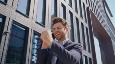 Akıllı telefon görüşmesine gülen heyecanlı bir adam güneşli iş alanında yürüyor. Mutlu iş adamı sokaklarda cep telefonu konuşarak harika haberler veriyor. Gülümseyen girişimci başarıya duygusal tepki veriyor.