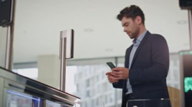 Girişimci turnikeden geçerken akıllı telefondan mesaj atıyor. Resmi takım elbiseli erkek yönetici ofis binasının elektronik kapılarını açmak için akıllı kaset kullanıyor. Cep telefonu girişi olan zengin bir işadamı.