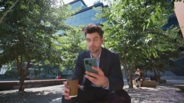 Şehir parkında kahve fincanı kapalıyken cep telefonu uygulamasına göz atan sakin bir serbest yazar. Yakışıklı iş adamı dışarıda dinlenirken e-postalarını kontrol ediyor. Zarif yönetici cep telefonu ekranı görünümlü.