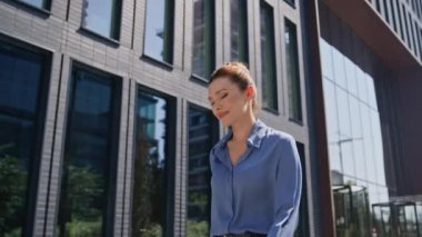 Mutlu iş kadını gülümseyerek güneşli caddede yürüyor. Çekici bayan ofis müdürü iş molasında sokakta geziniyor. Gülümseyen zarif kadın CEO modern iş bölgesinde dinleniyor..