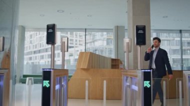 Güvenlik girişinden geçen bir iş adamı. Modern ofis, akıllı telefondan konuşuyor. Turnikenin elektronik kart okuyucusundaki zarif CEO kartı. Gülümseyen müdür güvenlik kapısı iş merkezine giriyor.