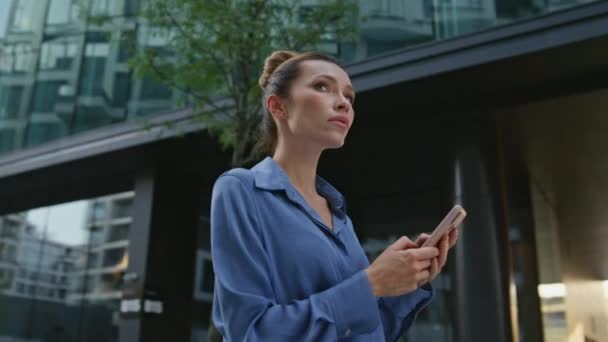 携帯アプリを使用して近代的な都市地区の場所を見つける女性 魅力的なビジネスマンは 立っているスマートフォン画面を見ています ソーシャルメディアを閲覧するスマートな女性 カメラが動き回る — ストック動画