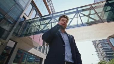 Modern metropolde konuşan zengin bir işadamı. Başarılı bir iş adamı açık havada telefonla sorunları çözüyor. CEO, ofisin dışında akıllı telefondan konuşuyor. Kamera hareket ediyor.