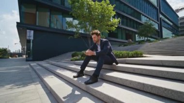 Kendine güvenen işyeri sahibi cep telefonuyla mesajlaşıyor şehir merkezindeki şehir merkezinde oturuyor. Zarif iş adamı iş yerinde akıllı telefondan açık havada mesaj atıyor. Sokak zoom 'unda telefonu kullanan yakışıklı adam.
