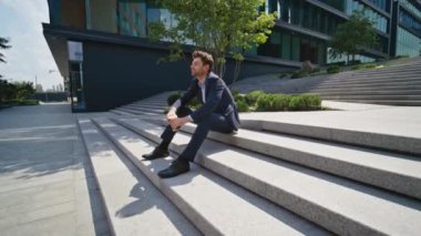 Düşünceli yönetici, kahve fincanını yakınlaştırarak şehir merkezindeki merdivenleri kırmaktan hoşlanıyor. Zarif, rahat bir iş adamı modern şehir merkezini tek başına dinlenirken izliyor. Yakışıklı adam şirket ofisinde dinleniyor.