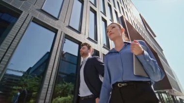 Zengin iş adamları güneşli bir sabahta modern kasaba bölgesinde yürüyorlar. Şehir caddesinde iş görüşmesi için acele eden bir çift ofis çalışanı. Tablet bilgisayar tutan zarif bir iş kadını. Ortaklık kavramı.