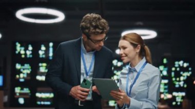 Bilgi teknolojisi uzmanları gece veri tabanında çalışıyorlar. Erkek kadın, elinde tablet cihazıyla internet hizmetlerinin bulut hesaplama tesisini izliyor. Bakım yapan meslektaşlar
