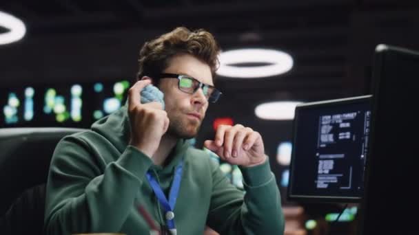 データセンターのクローズアップでシステム管理者の作業コンピュータを考える 後半の職場でアイデアを生み出すボールを持っている熱心なIt男性 Pcでキーボードのライティングコードを入力するメガネの集中コーダー男 — ストック動画