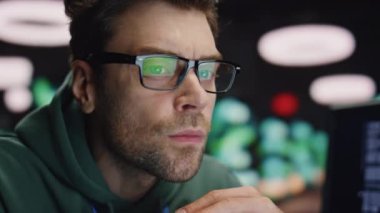Gece veri tabanında çalışan ciddi bir geliştirici. Gözlüklü bir adam işyerindeki bilgisayar monitörü programlama koduna bakıyor. Masaüstüne bakan yorgun IT programcısı işte hata buldu
