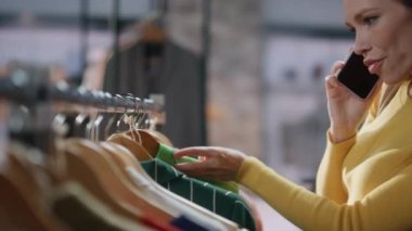 Alışveriş merkezindeki alışveriş rutininin keyfini çıkarırken cep telefonunu arayın. Moda mağazasından en yakın arkadaşıyla konuşan mutlu bir kadın. Modern mağazada yürüyen hoş bir bayan.