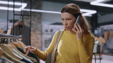 Sinirli bir alışveriş kadını giyim mağazasından cep telefonunu arıyor. Kadın müşteri elbiseleri butikte akıllı telefon görüşmesinde pahalı fiyatları tartışıyor. Şok olmuş alışveriş meraklısı bir elbise.