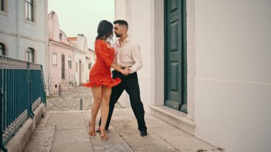 Şehirli dansçılar şehirde Latin Amerika tarzı dans ediyorlar. Kırmızı elbiseli güzel bir kadın zarif bir partnerle dans ederek kalçalarını çeviriyor. Korkuluklarda tutkuyla dolaşan profesyonel bir çift.