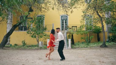 Samba dansçıları ağır çekimde enerjik danslar yapıyorlar. Açık havada Latin tarzı dans eden profesyonel sanatçılar. Güzel İspanyol esmer kadın çekici bir adamla baştan çıkarıcı bir şekilde hareket ediyor..