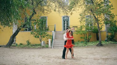 Şehir parkında Latin dansı yapan birkaç profesyonel. Tutkulu genç sanatçılar, enerjik salsa dansını yavaş çekimde yapıyorlar. Parlak esmer kadın sokakta İspanyol bir adamla baştan çıkarıcı bir şekilde hareket ediyor..