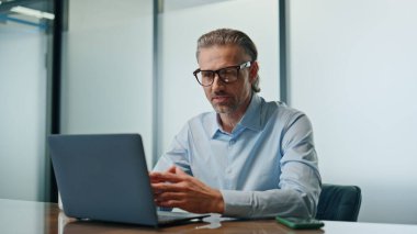 Mutlu iş adamı videosu kabineyi kapatıyor. Gülümseyen sakallı menajer video konferansının tadını çıkarıyor. Patron internet toplantısında konuşuyor. Lider kişi dizüstü bilgisayar kullanarak çevrimiçi röportaj yapıyor