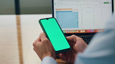Ofiste çalışan eller yeşil ekranlı telefonu yakın çekimde tutuyorlar. Bilinmeyen iş adamı masadaki banka hesaplarını kontrol eden mesajları okuyor. Kromakey telefon oturma yeri kullanan isimsiz girişimci