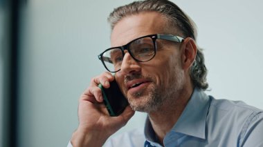 İş yerinde gülen işadamını arıyorum. Mutlu gözlüklü adam içeride cep telefonuyla konuşuyor. Tıraşsız finans müdürünün şirket ofisinde cep telefonuyla ilgili iyi haberleri tartıştığına eminim.