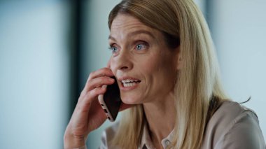 İş yerindeki portrede akıllı telefonu merak eden şaşırmış bir kadın. Açık alanda cep telefonu sohbetinde heyecanlı kazanan bayan duygusal konuşuyor. İş kadını harika sonuçlardan keyif alıyor. Yakın plan. Başarı konsepti 