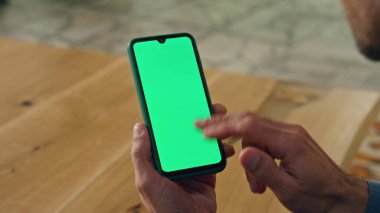 Dolaba yakın çekimde kullanıcı kromakey akıllı telefonu. İş adamı ofisinde şablon cihazını tutuyor. Tanımlanamayan işadamı sıcak iş yerinde yeşil ekran cep telefonu ağı kullanıyor.