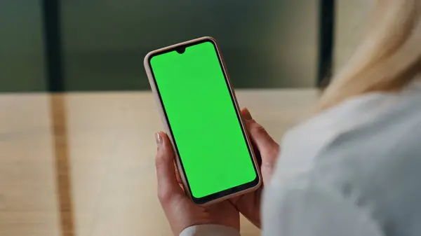 Lady looking green display phone indoors close up. Anonymous business woman hands holding mockup key cellphone. Boss arms carrying chroma screen smartphone. Unknown person watching template telephone