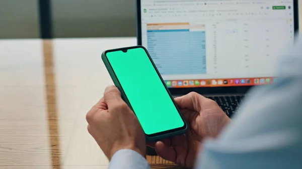 Employee hands holding greenscreen telephone at office closeup. Unknown business man reading messages checking bank account at table. Anonymous entrepreneur using chromakey phone sitting workplace