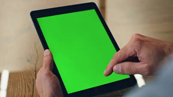 Boss finger swiping greenscreen tablet at office. Closeup anonymous man surfing web using chroma key tab device display. Director hands browsing internet scrolling mockup computer online at workplace