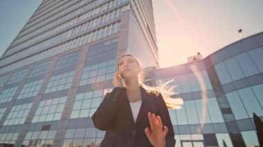 Güneşli şehir bölgesinde cep telefonuyla konuşan şık bir iş kadını. Çekici bir bayan yönetici, dışarıda gün ışığında akıllı telefondan danışmanlık yapıyor. Mutlu bayan patron cep telefonuyla işi tartışıyor.