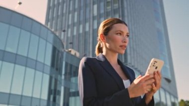 Akıllı telefon sitesinde sörf yapan kadın yönetmen Sunny Caddesi 'nde toplantı bekliyor. Kapatın. Dışarıda cep telefonu mesajı okuyan genç ve güzel bir iş kadını. Kendine güveni tam bir kadın gün ışığında telefon ekranına bakıyor..