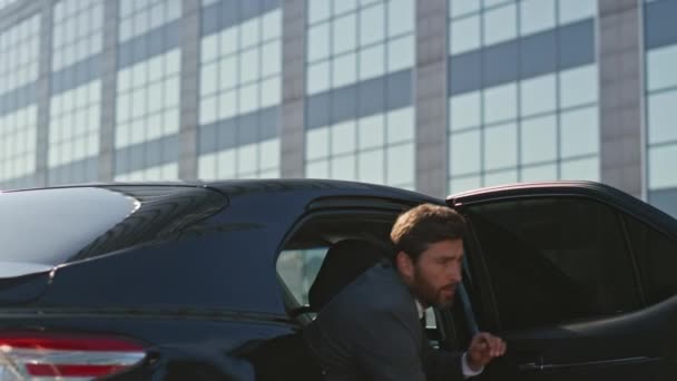 車を離れた金持ちは近代的な会社のオフィスに近づきました 成功したビジネスマンは 日当たりの良い通りに高価な自動車を脱出します ひげ付きの裕福なボス ドアを閉める豪華な黒い自動車 — ストック動画