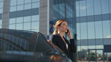 Modern ofis binasının yakınında güzel bir iş kadını cep telefonunu arıyor. Başarılı bir iş kadını lüks bir arabanın önünde akıllı telefondan konuşuyor. Mutlu zarif bayan dışarıda cep telefonuyla konuşuyor..