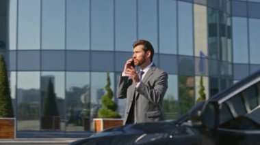 Zengin patron konuşuyor. İş yerinde arabaya biniyor. Kendine güveni tam bir işadamı güneşli caddede lüks bir otomobilin kapısını açıyor. Başarılı bir işletme sahibi açık havada akıllı telefon konuşuyor..