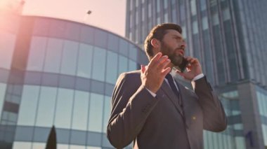 Akıllı CEO, modern ofisin dışında akıllı telefondan iletişim kuruyor. Kendine güvenen sakallı işadamı, güneşli caddede duran ortakları arıyor. Profesyonel iş danışmanı telefonla teklifini tartışıyor.