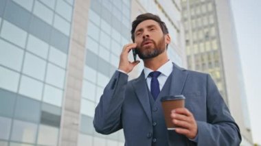 Neşeli menajer kahve fincanıyla modern caddede yürümeyi bitirdi. Gülümseyen işadamı cep telefonu konuşmasından sonra içecek servisi yapıyor. Sakallı mutlu adam harika haberler duyuyor, başarıyı hissediyor..