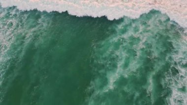 Turkuaz okyanus suyu çok yavaş çekimde sahile doğru akıyor. Resmedilmeye değer mavi dalgalar yaz doğasına doğru hızla sıçrıyor. Beyaz deniz köpüğü deniz kıyısına doğru hareket ediyor. Tropik deniz manzarası.