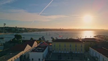Günbatımı panorama yatları liman drone görüntüsü. Deniz kıyısında bir tatil köyü akşam güneşinde kurulmuş. Sakin su, sıcak güneş ışınlarını yansıtıyor. Yazlık yelkenlilerin üzerinde güzel bir gün batımı gökyüzü var. 