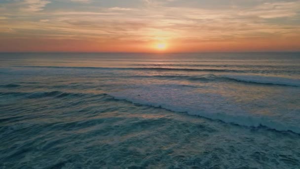 ゴールデンサンセットは 海の地平線上の空を眺めることができます 美しい夏の日没は 超遅い動きで海岸に転がる泡立った海の波を反映しています 穏やかな海洋の夕方に沈むオレンジの太陽 — ストック動画