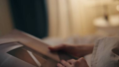 Kapalı eller sayfayı içeride çeviriyor. Evinde kitap okuyan bir kız öğrenci. Tanımlanamayan kız okuyucu elinde hafta sonu dinlenme romanı tutuyor. Huzurlu insan rahatla boş zamanlarında edebiyat oku.