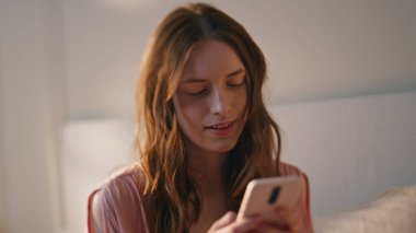 Yatakta cep telefonuyla mesajlaşan bir kız. Sabahın köründe akıllı telefon yazan gülümseyen genç bir kadın. Tasasız sakin ergen mesajlaşması evde tek başına eğleniyor. Günlük rutin kavram.