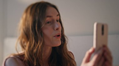 Gülümseyen ergen evde video konuşması yapıyor. Neşeli kız, güneşli bir sabahta elinde cep telefonuyla arkadaşlarıyla konuşuyor. Kaygısız mutlu kadın çevrimiçi sohbetten zevk alıyor. Dijital yaşam tarzı kavramı.