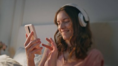 Akıllı telefondan şarkı çalma listesini arayan mutlu kız. Enerjik kadın evdeki kulaklıklarla en sevdiği melodiyle dans ediyor. Kaygısız neşeli genç gözlerini kapatıyor ve sabah kulaklıkları dinliyor.