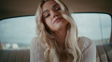 Arka koltukta rahatlayan muhteşem sarışın modelin portresi klasik otomobilde. Çekici genç bayan gezgin, beyaz elbiseli, eski model bir arabada oturuyor. Güzel, klas görünümlü kamera..