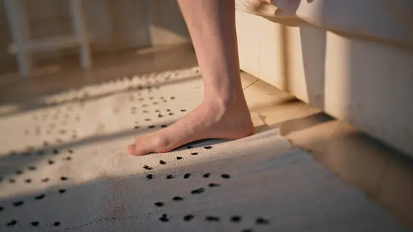 Woman legs stepping bed in sunlight closeup. Unknown woman wake up early morning walking carpet. Slim female feet get up going room floor. Serene awake person start new day. Home lifestyle concept.