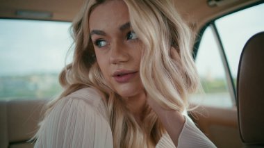Çekici kadın yolcunun portresi arka koltukta oturan kamera görünümlü. Klasik araç kuaföründe poz veren güzel, rahat sarışın manken. Kendine güvenen sakin kız seyahatin tadını çıkar.