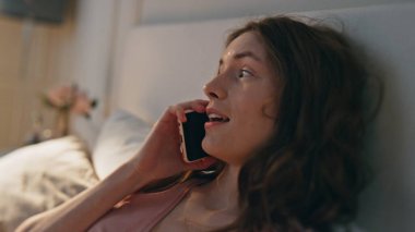 Ev kızı cep telefonuyla konuşuyor. Yatakta gülen, gevşemiş güzel bir kadın sohbetten zevk alıyor. Mutlu güzel model yataklı yatak odası hafta sonu planlarını konuşuyor. Neşeli kadın akıllı telefondan konuşur.