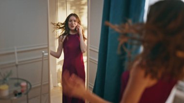 Aynada akıllı telefondan konuşan gülümseyen kız. Mutlu kadın parti kutlaması için hazırlanıyor. Romantik elbiseler deniyor. Neşeli model akşam planlarını konuşuyor. Moda yaşam tarzı konsepti 