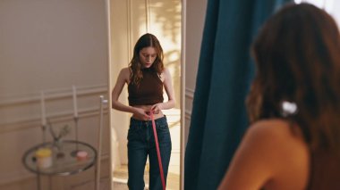 Bel ölçüsünü bantla ölçen kadın yansıması. Mutlu ince model kilo kaybı mükemmel vücut şekline hayran kalıyor. Çekici kız evde fitness başarısını analiz ediyor. Belirleyici başarı konsepti